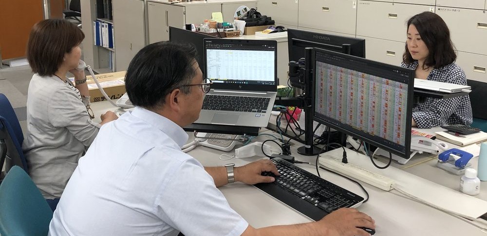 ノートパソコンを囲んで打ち合わせをする社員たち